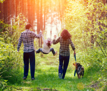 Happy family walking with dog in the forest